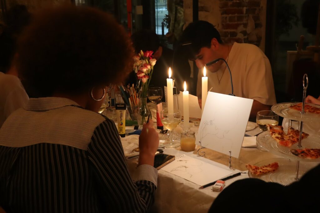 Invités peignant autour d’une table aux bougies